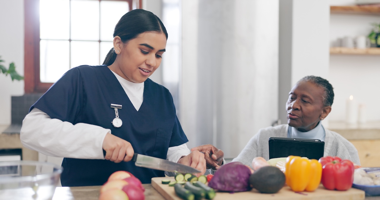 Caregiver, cooking and senior adult woman in home with healthy food, vegetables and nutrition in healthcare.