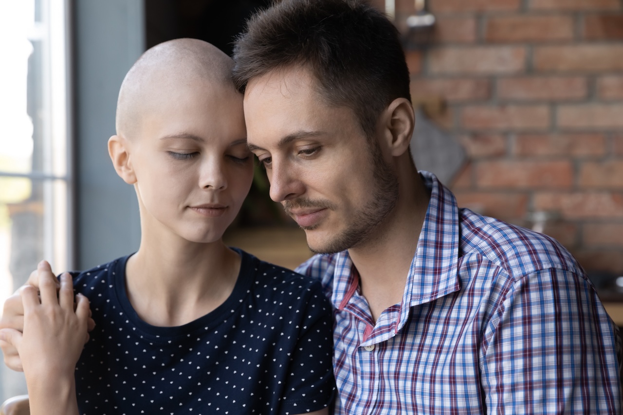 Caring supportive young husband embraces wife who is going through chemotherapy
