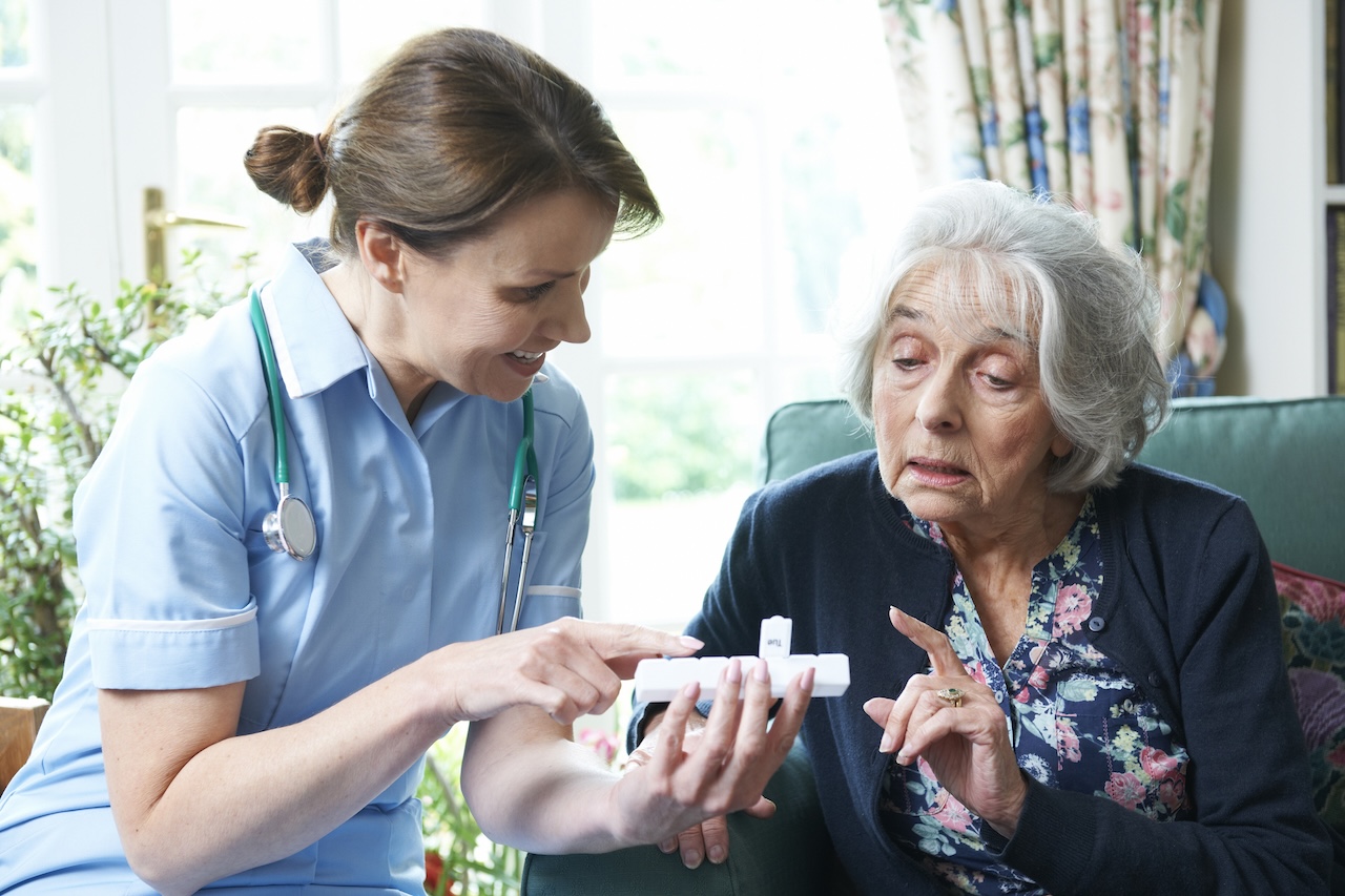 Nurse Advising Senior Adult Woman On Medication At Home