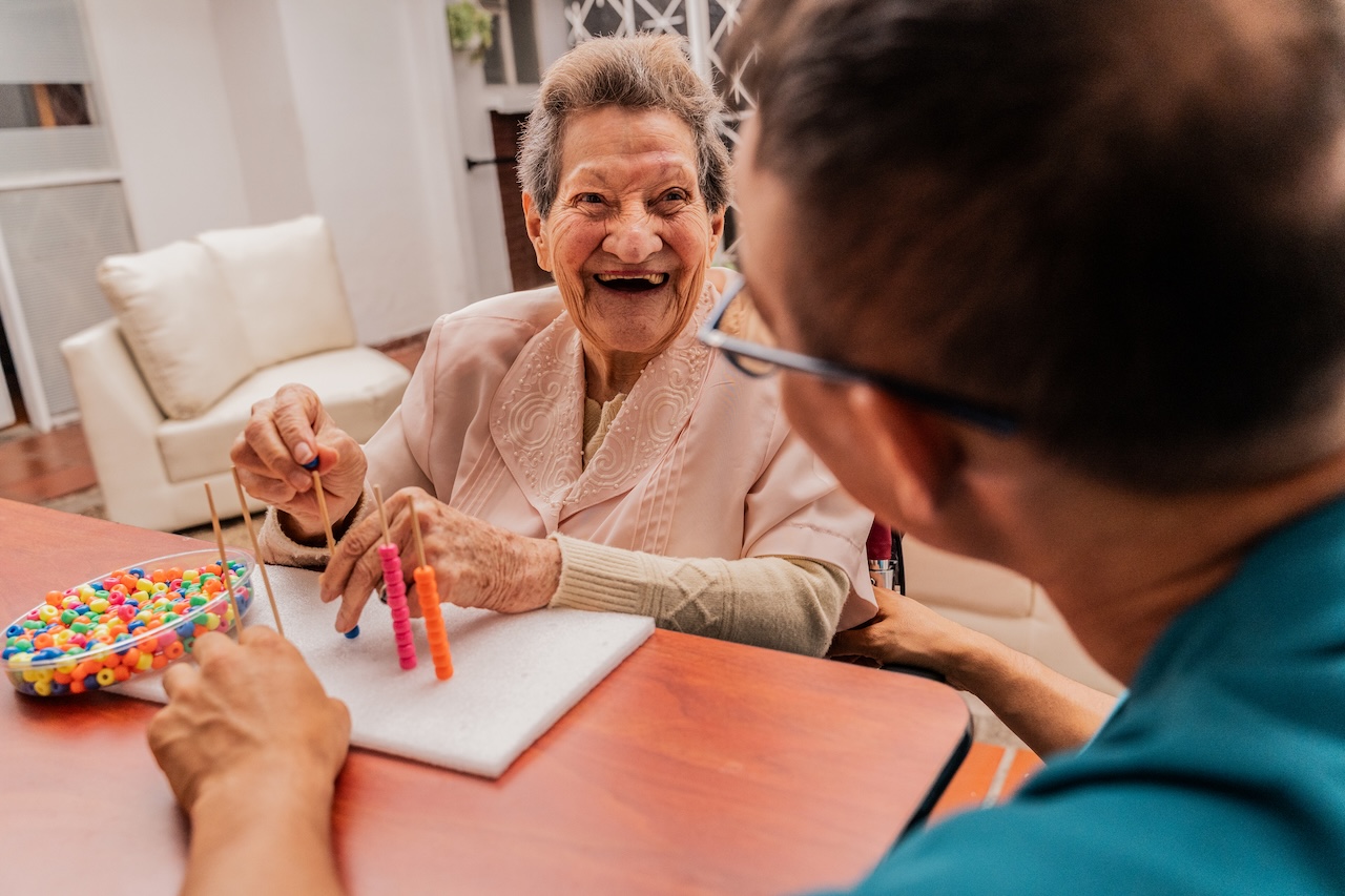 Senior adult woman and caregiver playing with a bead game